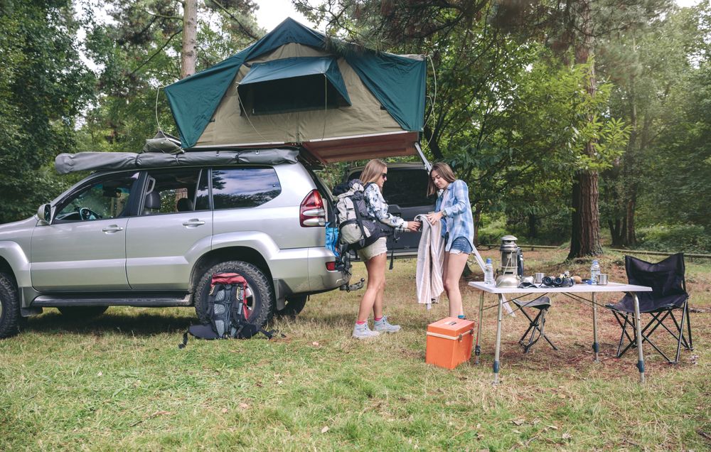 Young women in campsite packing blanket for hiking