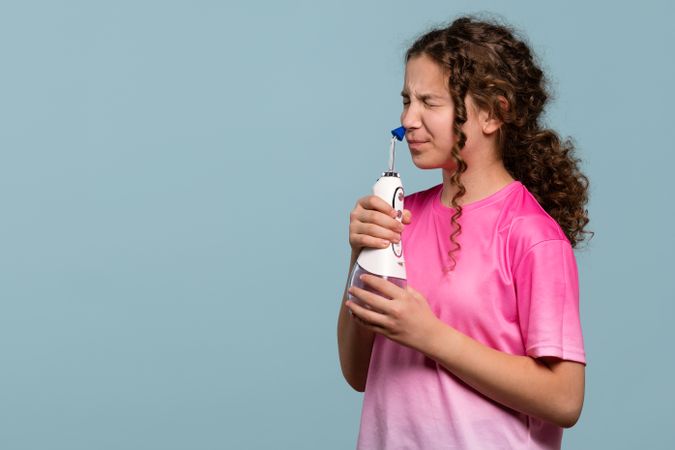 Young girl grimacing while using an oral irrigator