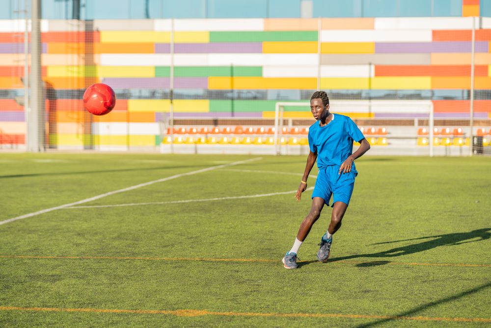 Black teenager juggling football ball