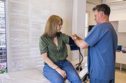 Male doctor is putting a blood pressure meter on his patient in hospital.