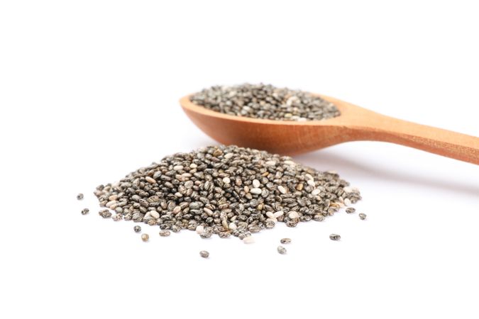 Chia seeds and wooden spoon isolated on blank background