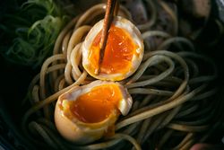 Halves of soft boiled egg on noodles