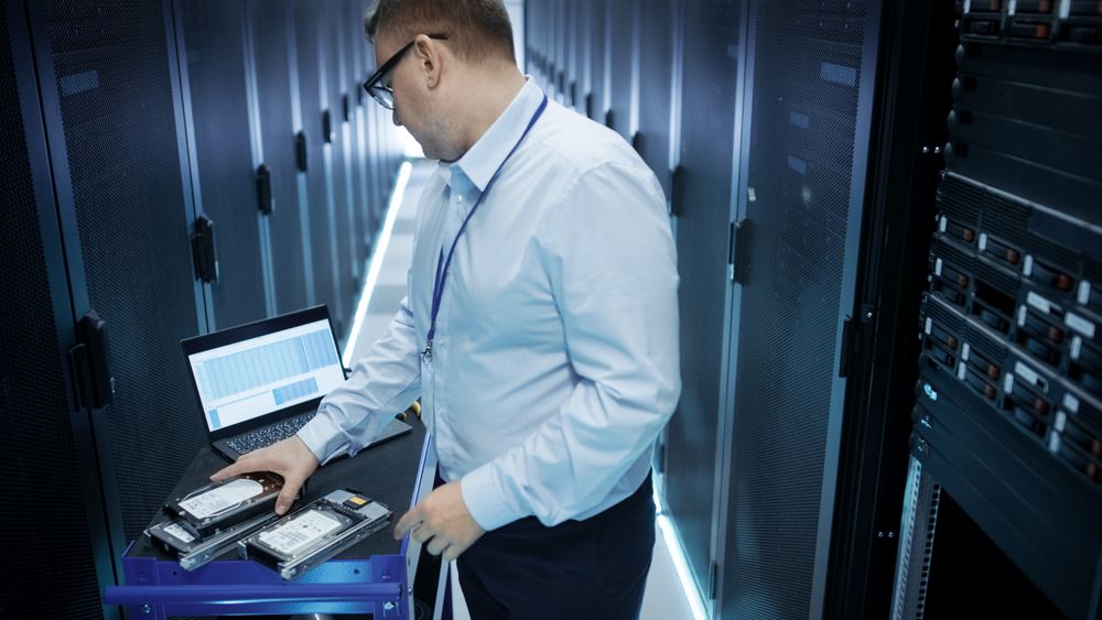 IT Engineer Taking Hard Drives off the Crash Cart and Installing Them into Rack Server.
