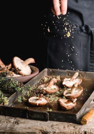 Cook preparing fresh brown mushrooms for baking