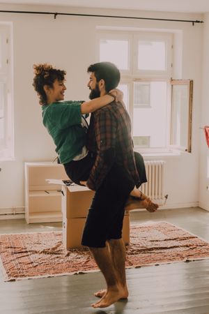 Happy couple embracing in room next to cardboard boxes