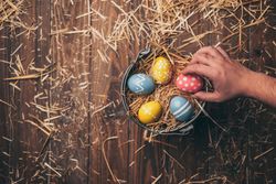 Hand placed Easter eggs on bucket with straw