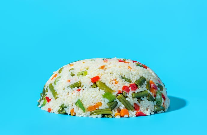 Vegan dish, rice with a mix of vegetables isolated on a blue background