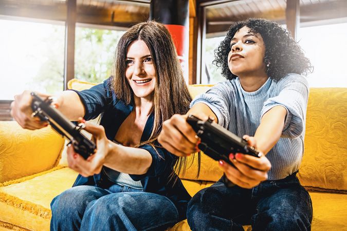 Cheerful adult friends having fun playing on console video games sitting on the sofa