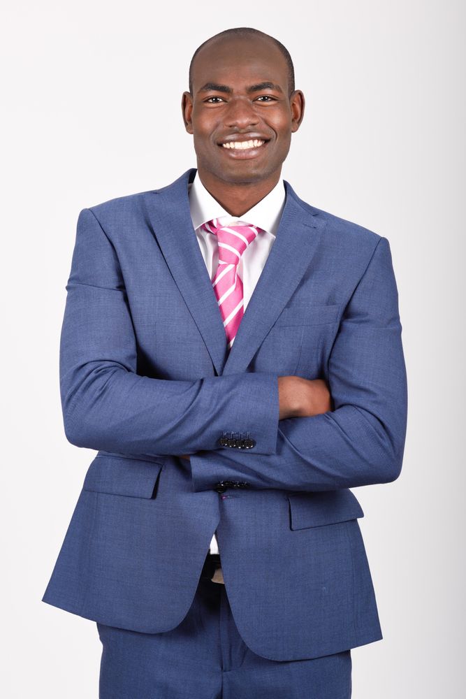 Smiling male in business attire standing with arms crossed