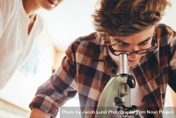 Male student looking at slides through a microscope in class bemEEb