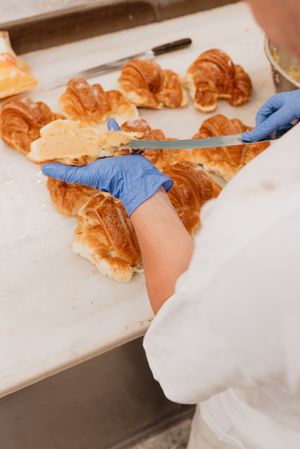 Crop confectioner smearing jam on croissant