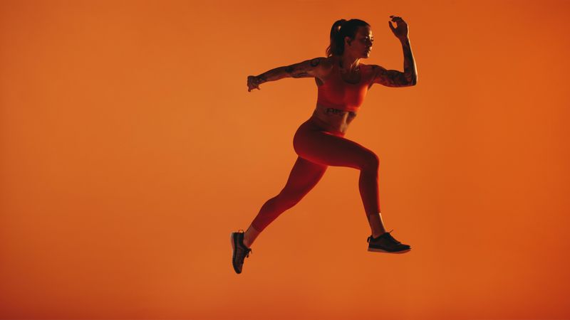 Female sprinter taking stride forward while running