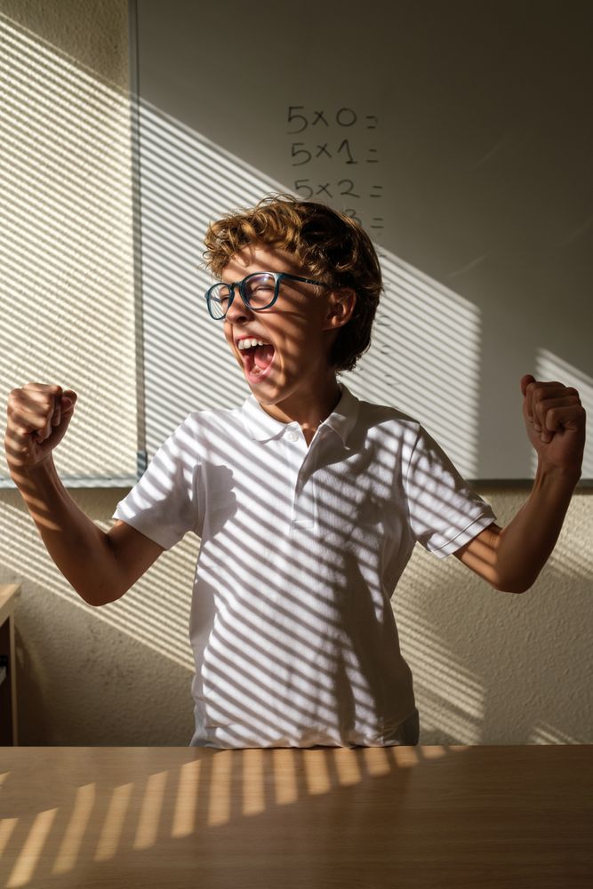 Delighted schoolboy celebrating victory in classroom