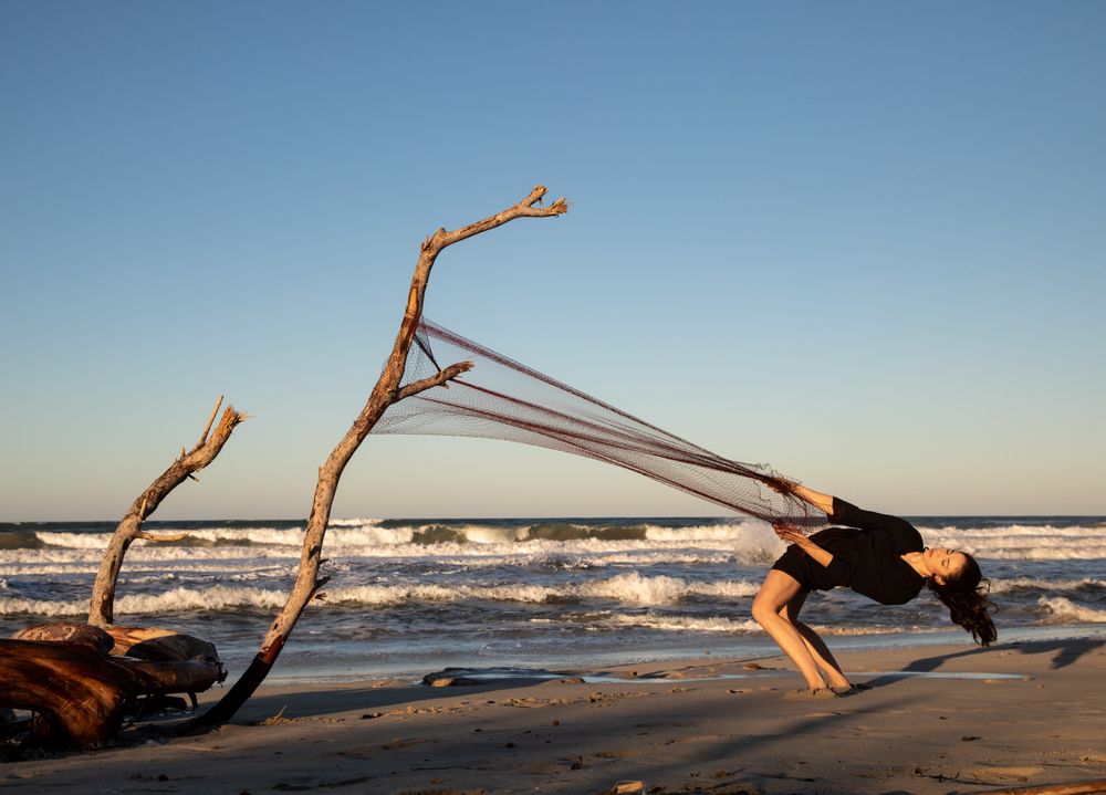 Woman in fishing net fixed on twig near water on shore