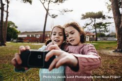 Little girls taking selfie using old camera at the park 0K6A7b