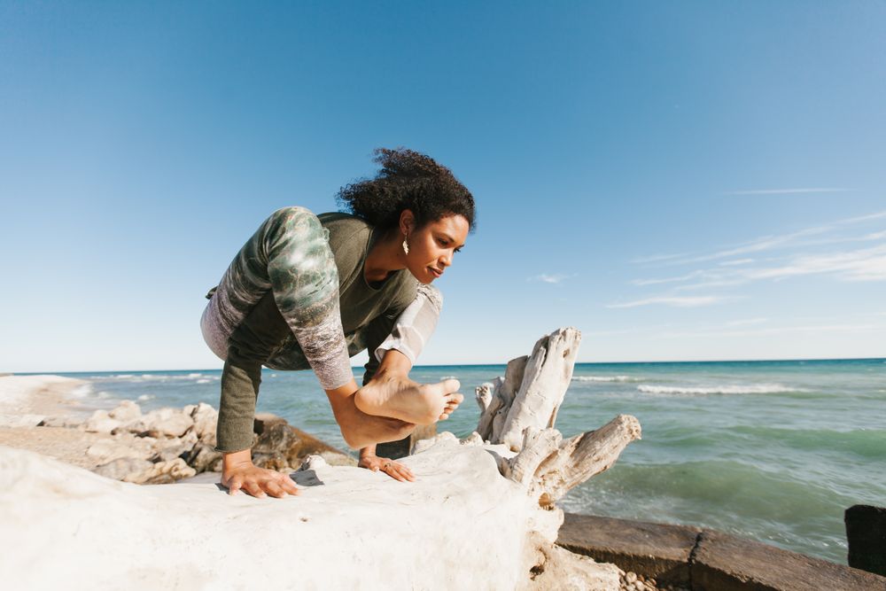 Sportive woman performing yoga posture on stones in nature