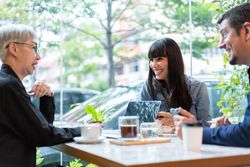 Business sales team having meeting with older woman in the coffee shop