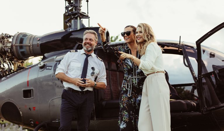 Beautiful women standing by helicopter with pilot