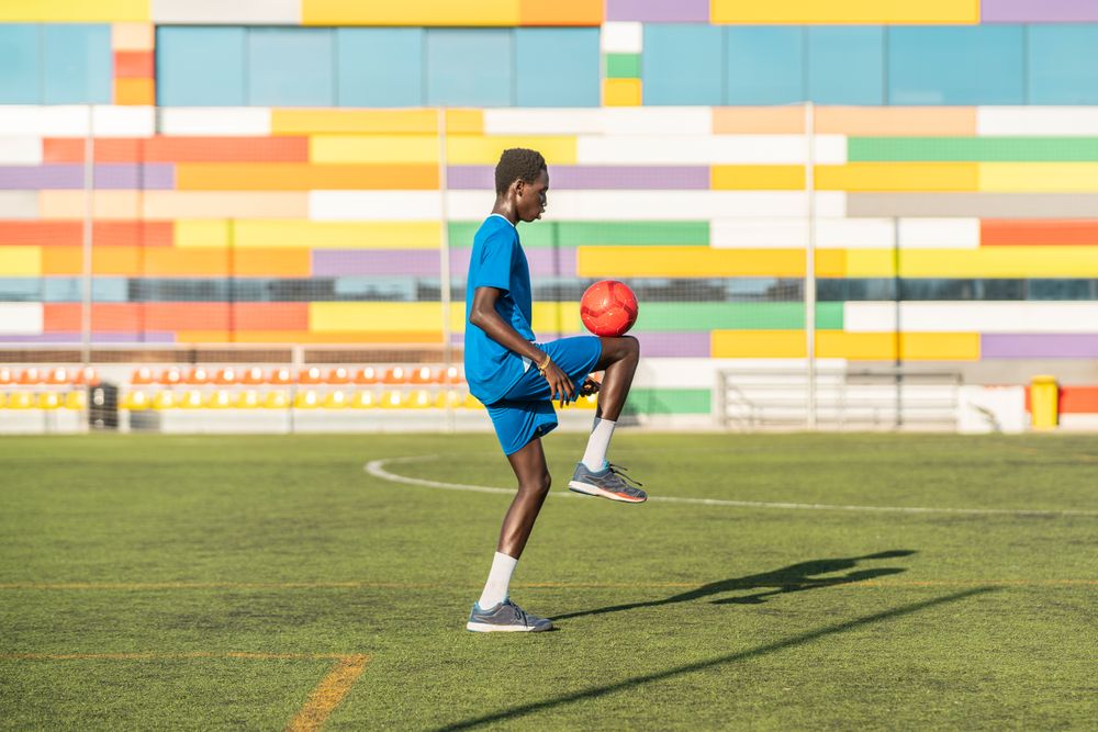 Black teenager juggling football ball