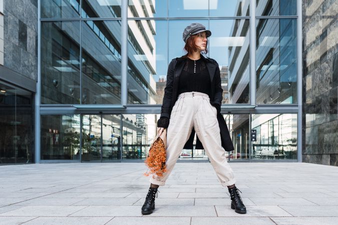 Stylish female holding flowers on street
