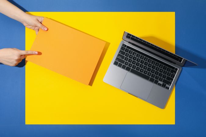 Top view banner of woman holding yellow paper next to laptop on blue table