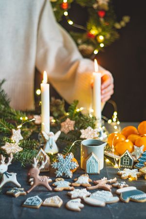 Cropped shot of person placing taper candle on table with cookies