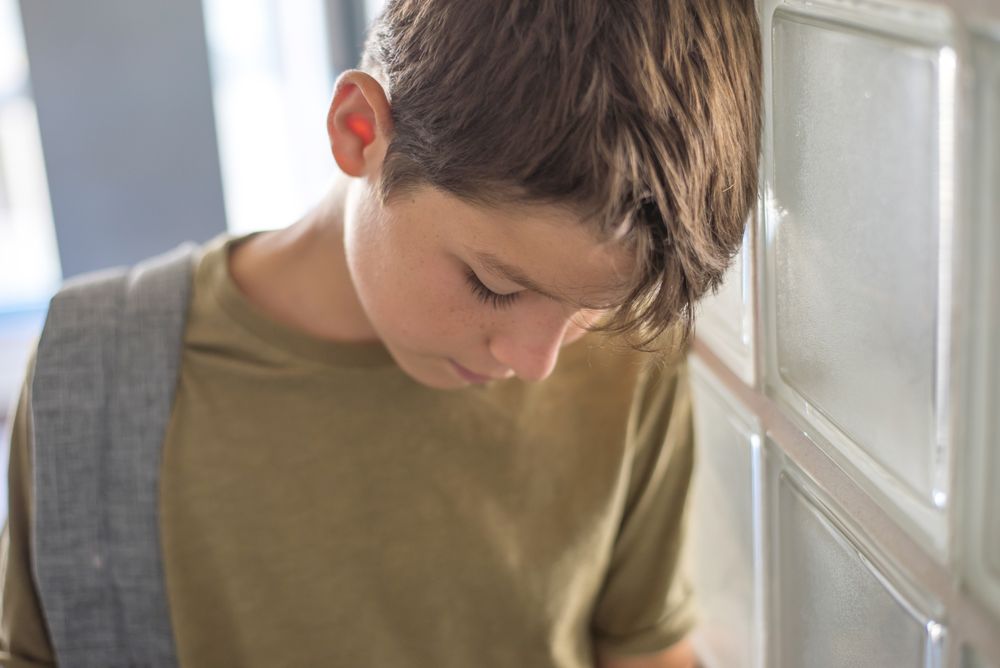 Teenage male with head down in sadness or tiredness in school