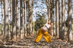 Concentrated adult expectant mother practicing yoga in park
