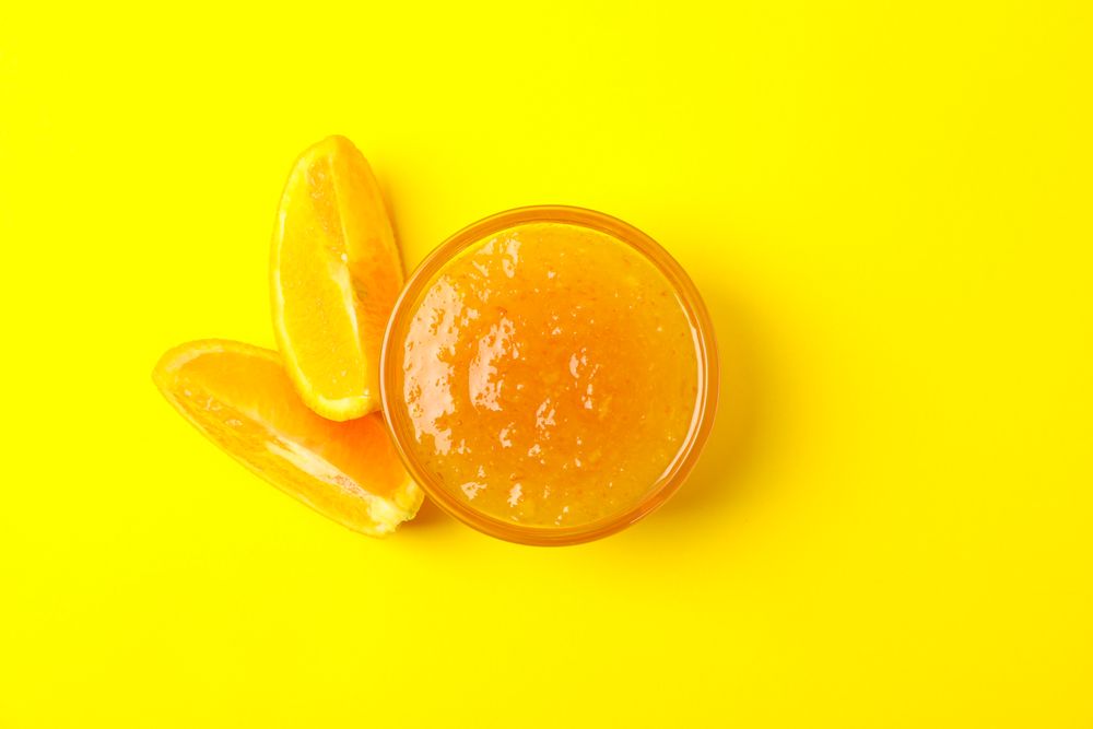 Delicious orange jam on yellow background, top view