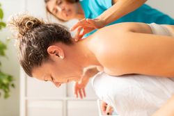 A woman performs an exercise, guided by her physiotherapist, during a session at the physiotherapy clinic