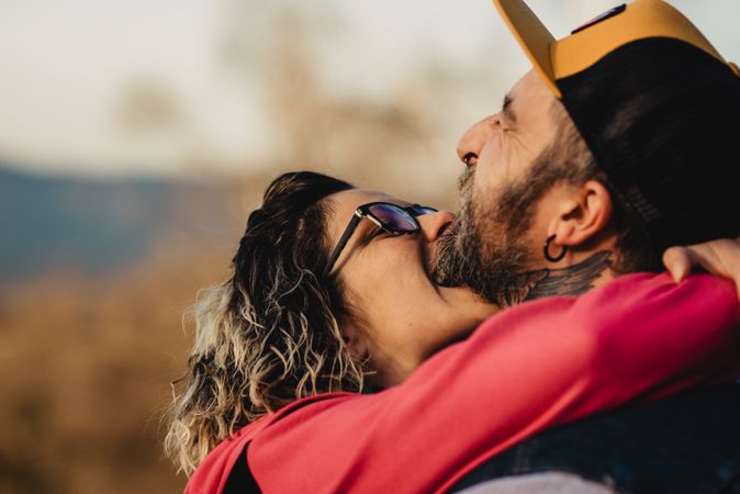 Happy couple hugging and kissing near tree in park