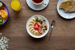 Juice and plate with granola and fruits on table