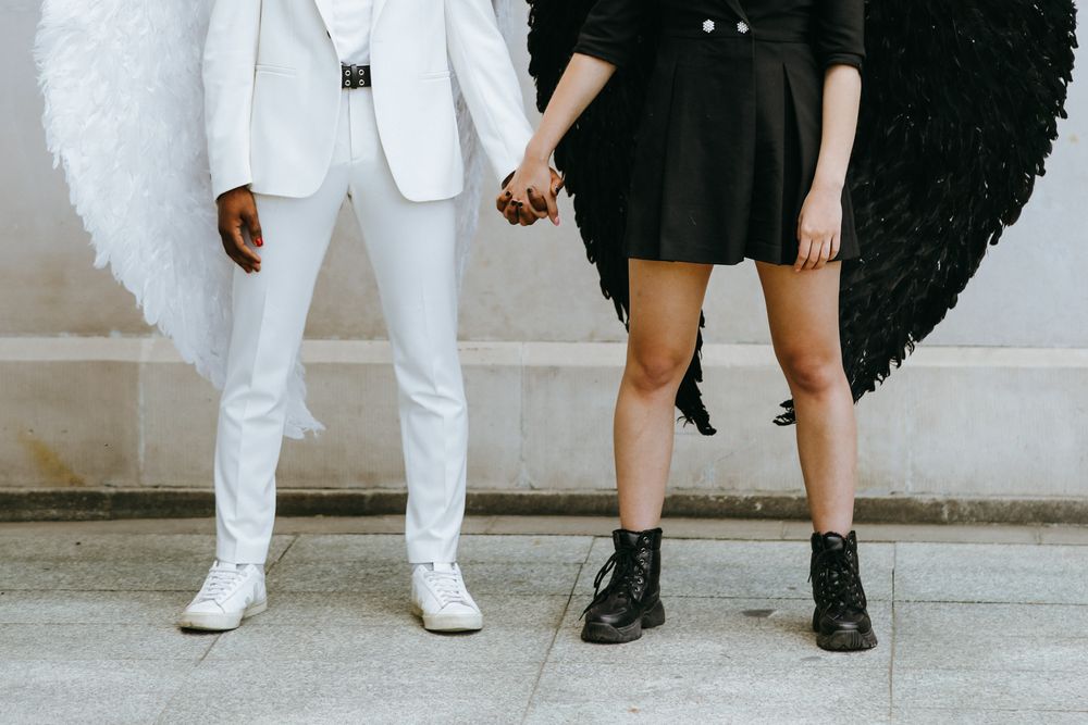 Cropped image of man in suit with light wings and woman in dress with dark wings