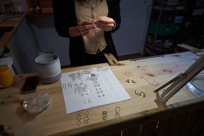 Crop artisan packing jewelry into plastic bags on table