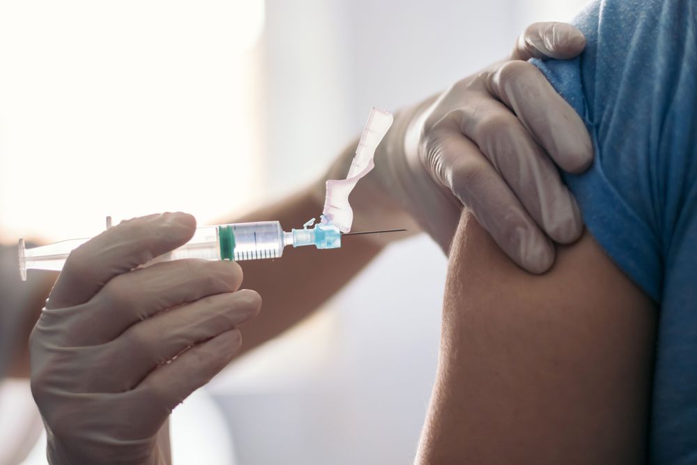 Vaccine in injection needle. Doctor working with patient's arm.