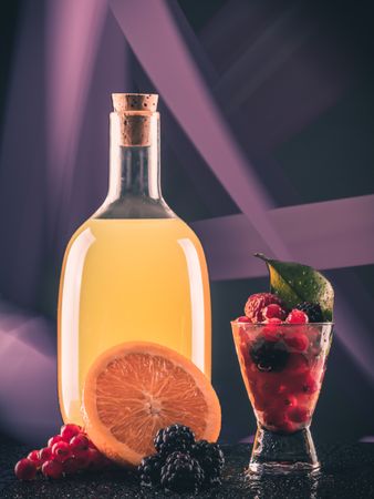 Bottle with drink near shot and fruits