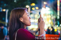Woman taking photo with smartphone in the city during nighttime 43BeO5