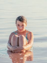 Teenage girl sitting in fresh water in sunny day