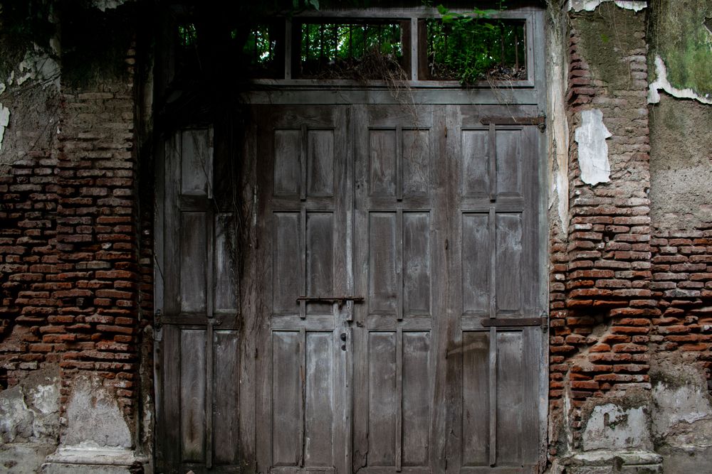 Big old broken wooden door on brick wall of historical building located in Kota Lama, Semarang City, Indonesia.