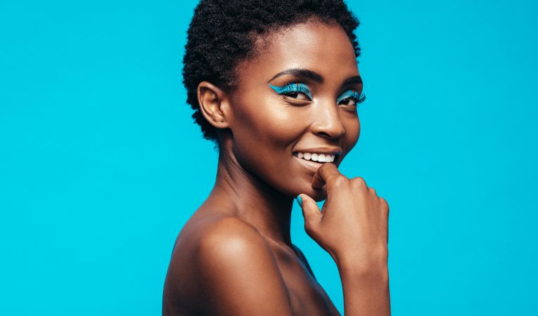 Close up of woman with makeup smiling against blue background