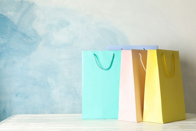 Color bags on table against blue background, copy space