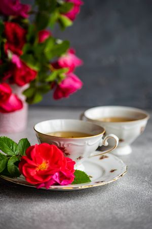 Side view of tea in cup & saucer with red roses and copy space