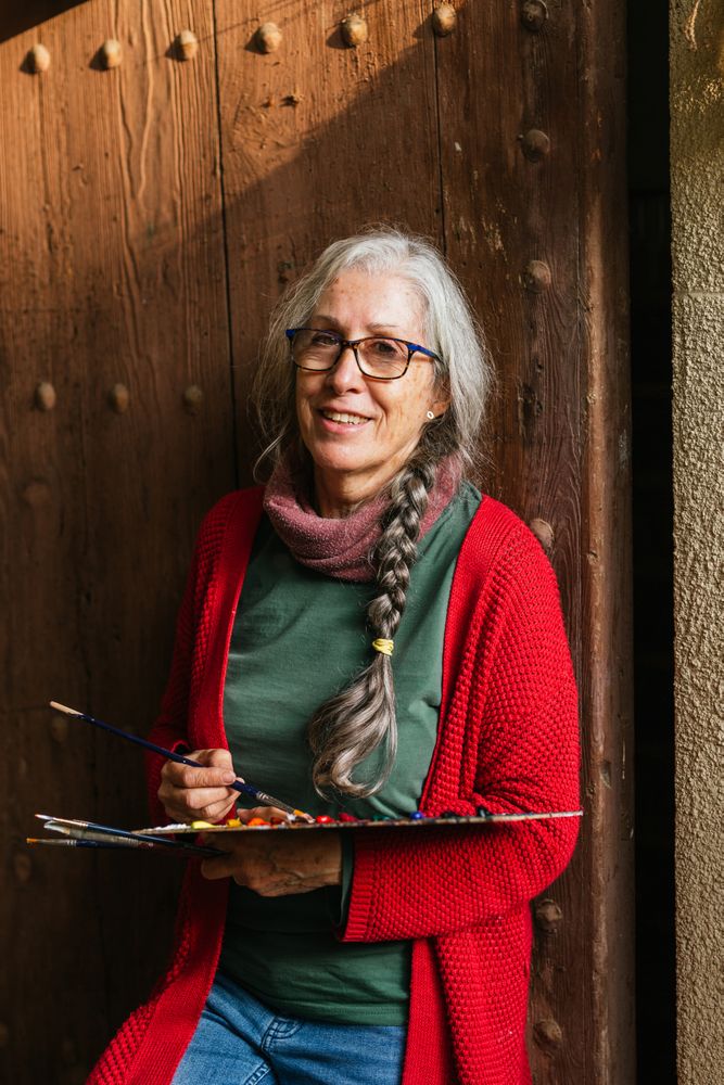 Cheerful painter with paint palette looking at camera