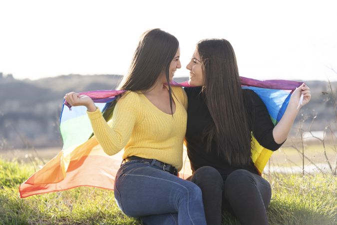 Young female couple with gay flag