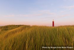 Red lighthouse from afar on green grass field 4dk3E5