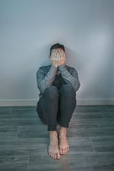 Man crying while covering his face with hands sitting on the floor