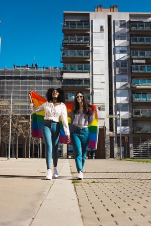 Female couple with rainbow flag walking in city