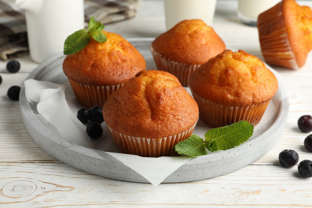 Composition with muffins and milk on plain wooden background