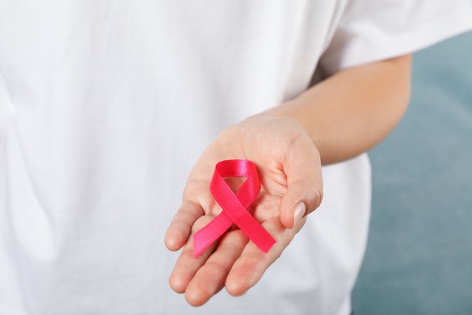 Person in t-shirt hold awareness ribbon against blue background