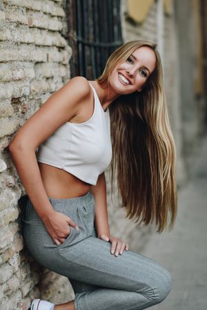 Long haired smiling woman leaning on wall outside
